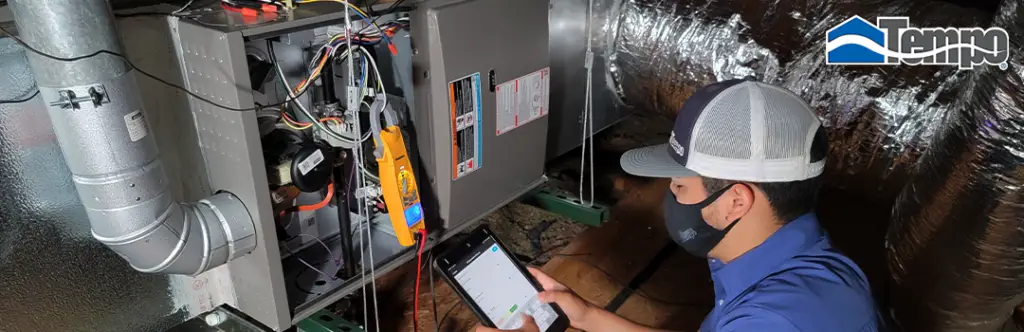 alt="Tempo Air Technician performing a rutinary maintenance to an HVAC system installed in the attic of a house.