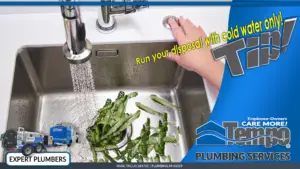 Cucumber shavings being flushed down garbage disposal with cold water.