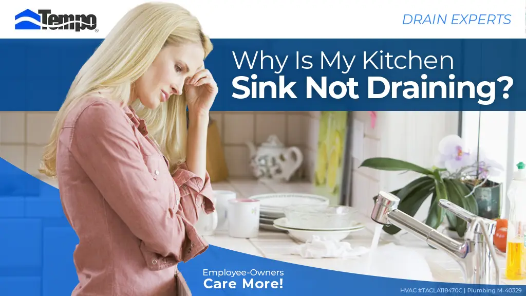 Woman holding head in distress looking at kitchen sink that's not draining.